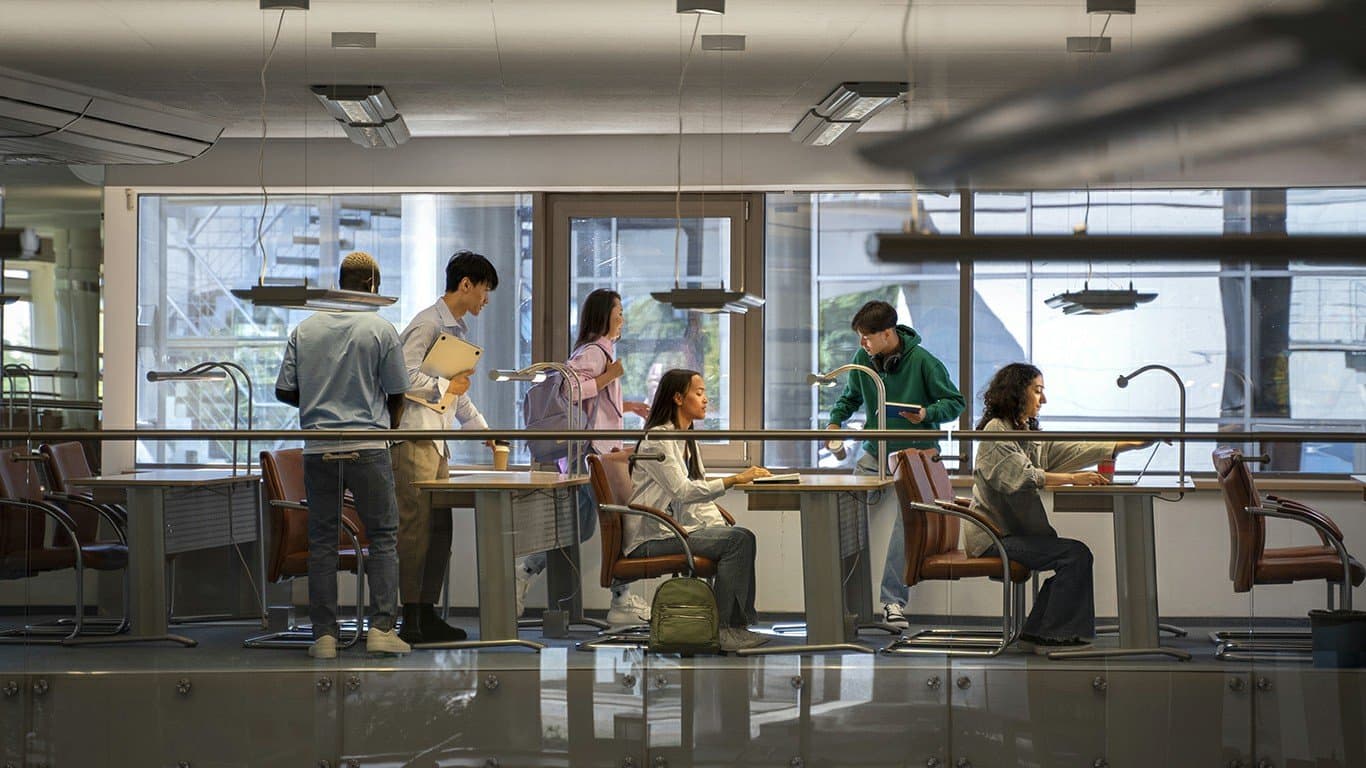 People working at laptops in a bright, glass-walled office
