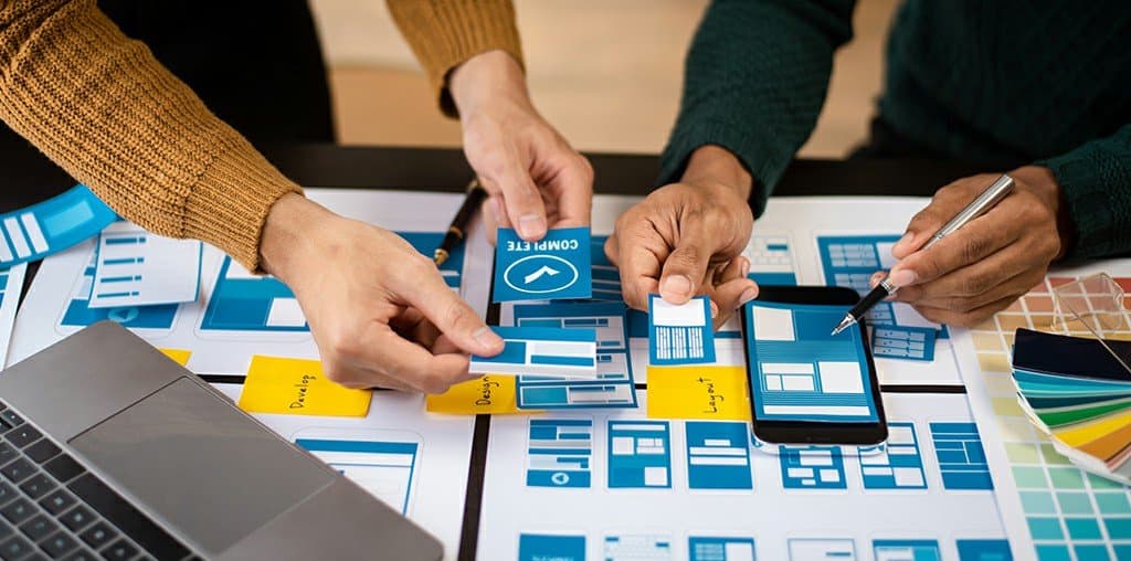 Designers laying out website wireframes and a colour palette on a table